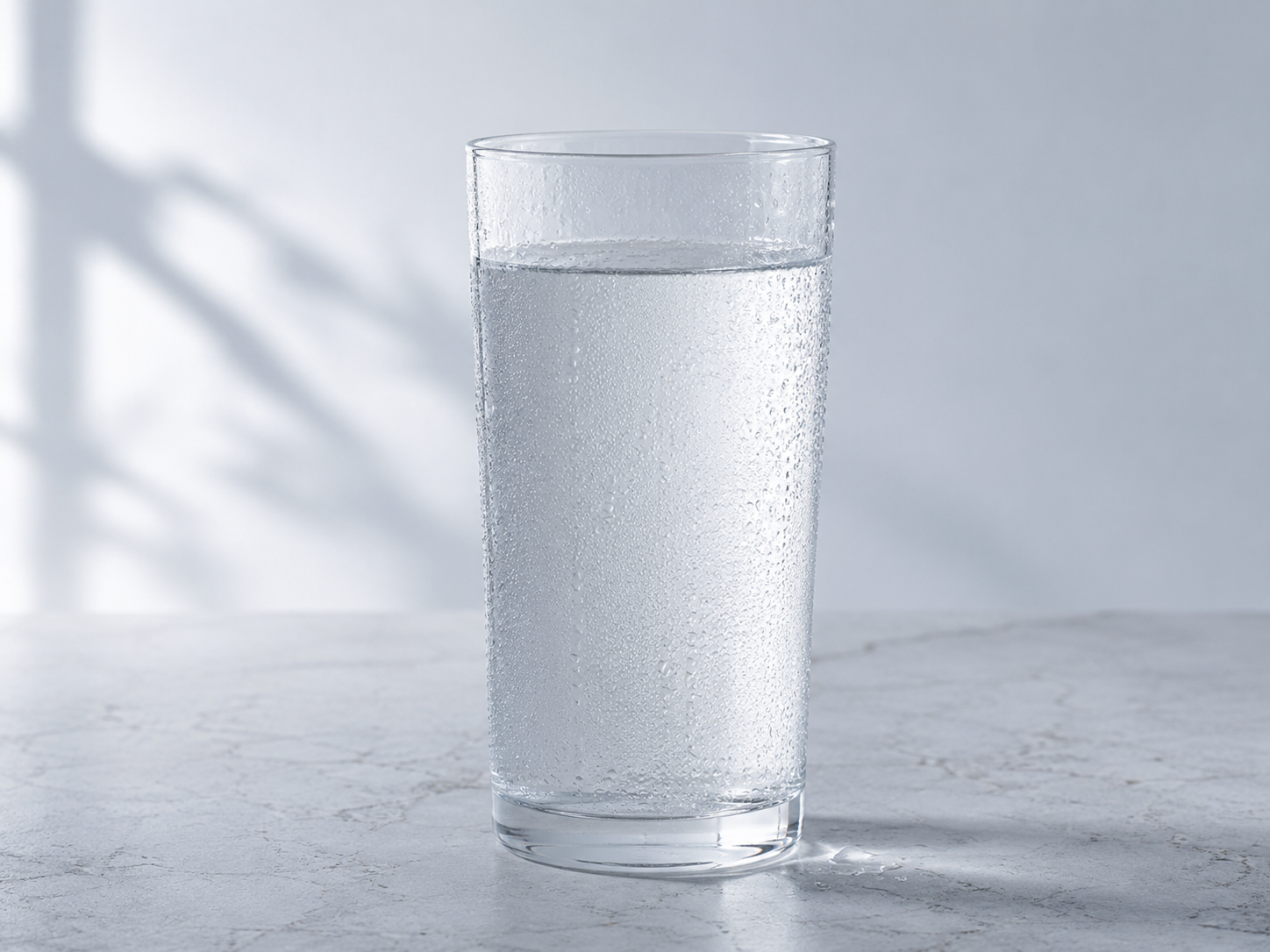 Vaso de vidrio con agua pura y transparente sobre mesada de cocina luminosa
